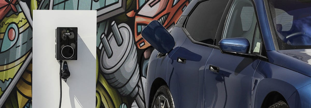 Electric charger and blue BMW car parked outside colourful graffiti background
