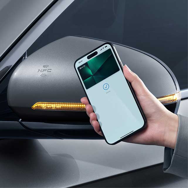 Hand holding phone next to car mirror