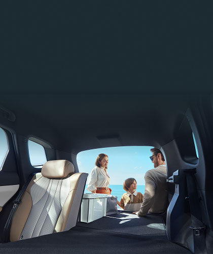 View of inside of car with rear seats down and Family putting things in boot