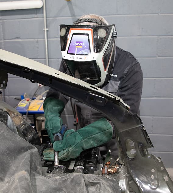 Staff member with protective mask working inside bonnet of car