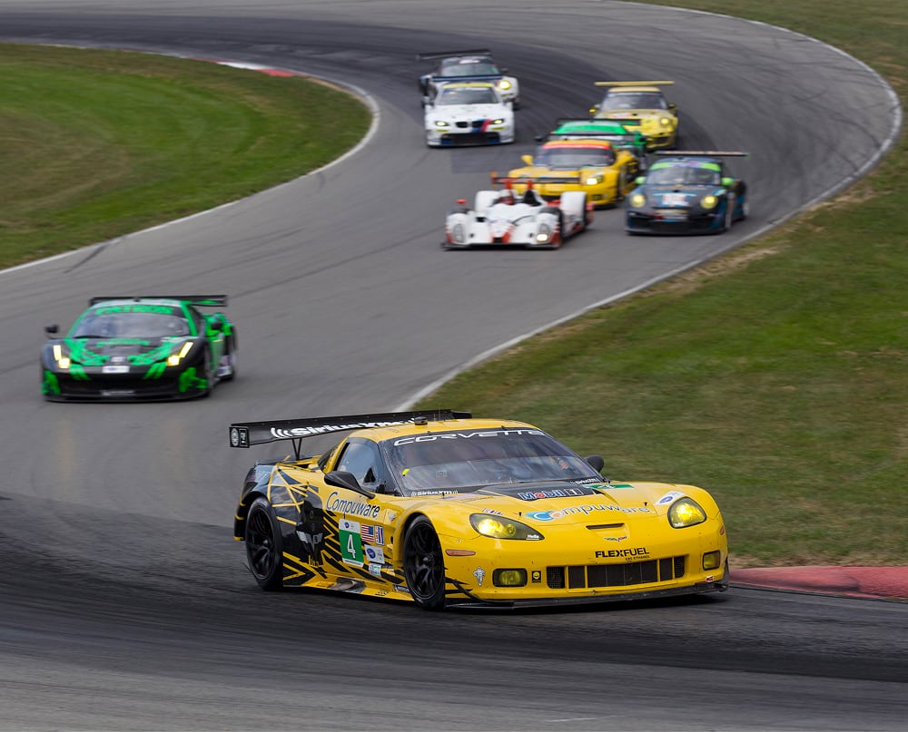 Yellow Corvette race car speeding on a curved race track