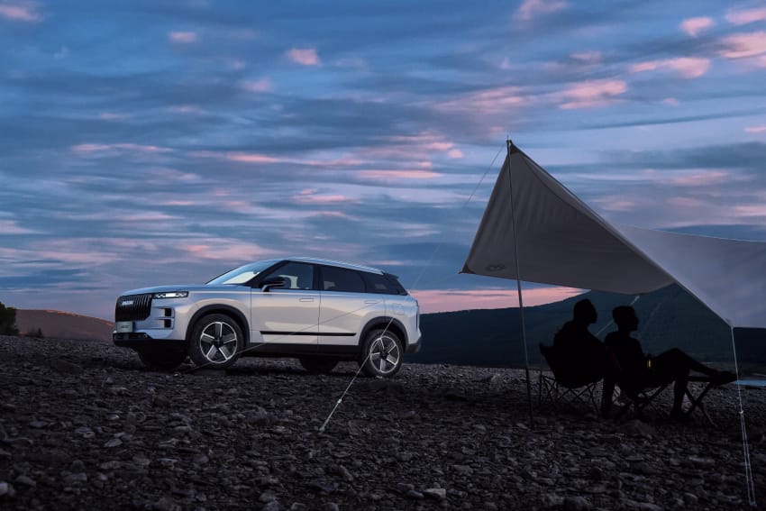 Silver JAECOO 7 on campsite with two people sitting camp chairs