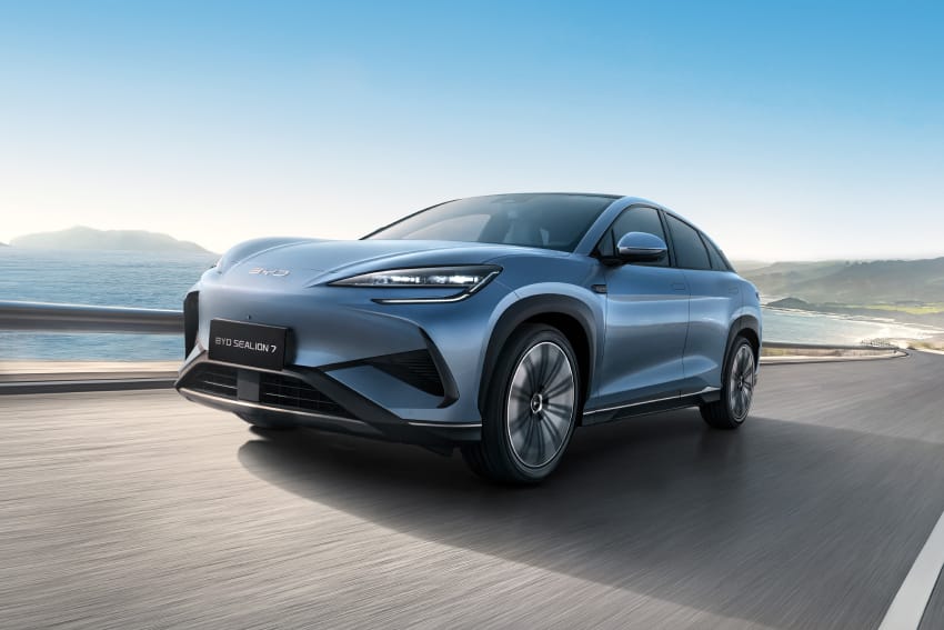 Angled front view of silver BYD Sealion 7 driving along coastal road