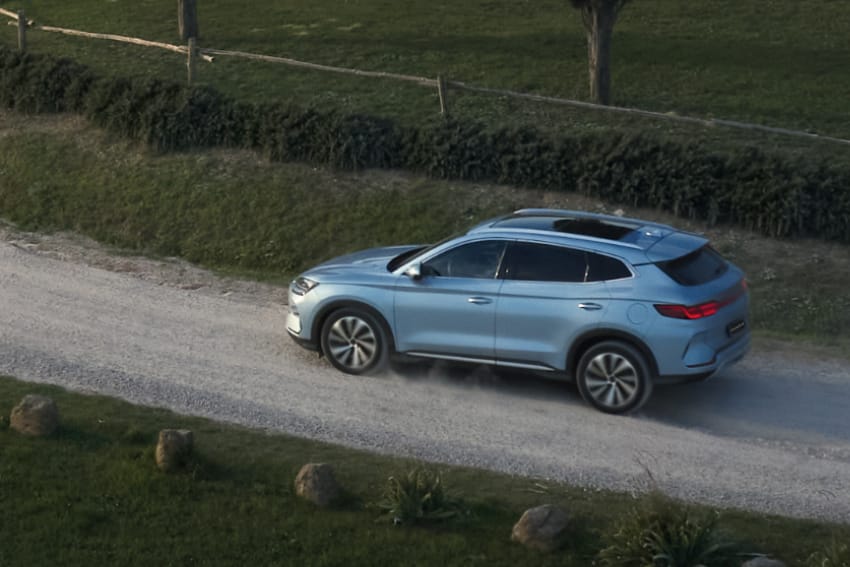 Aerial side on view of BYD Seal-U drving along gravel road in countryside