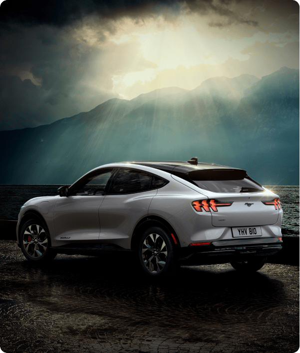 Angled rear shot of silver Ford Mustang Mach-E with hilly background