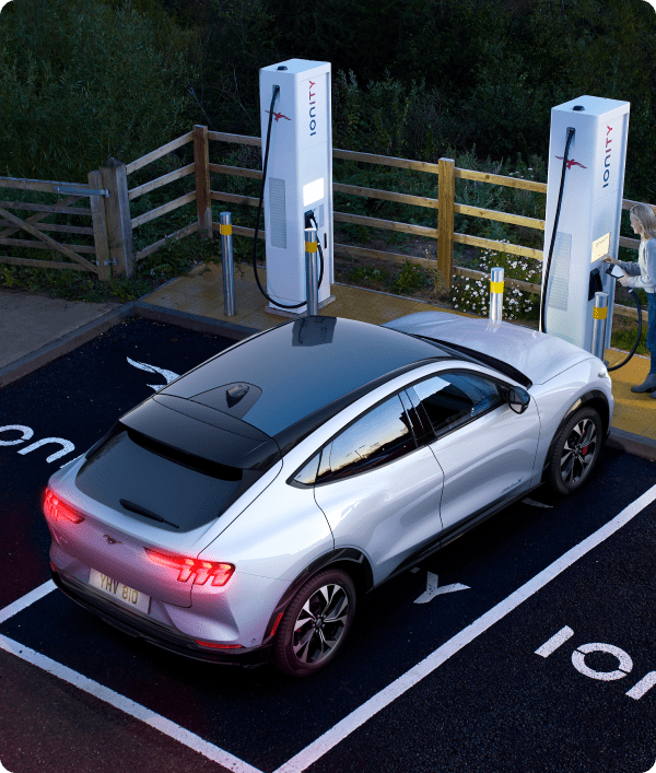 Aerial angled rear shot of silver Ford Mustang Mach-E charging