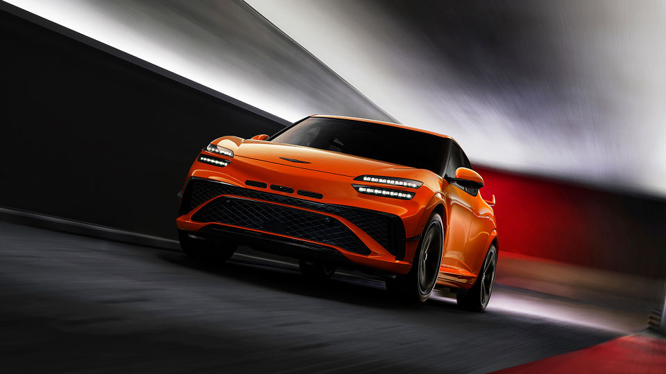Bright orange Genesis GV60 Magma driving through a tunnel