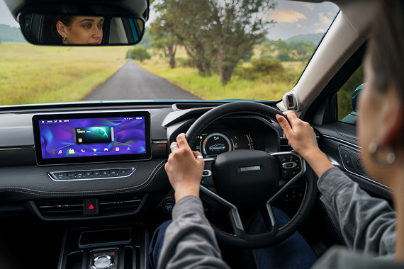 Woman in a denim jacket driving Haval Jolion down a country road