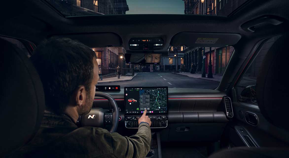 Driver using navigation system of Hyundai IONIQ 3 while driving through street at night