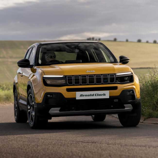 Angled front shot of yellow Jeep Avenger driving briskly around a corner