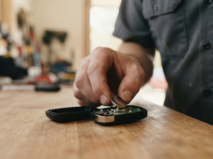 Car key on wooden surface with auto locksmith hand