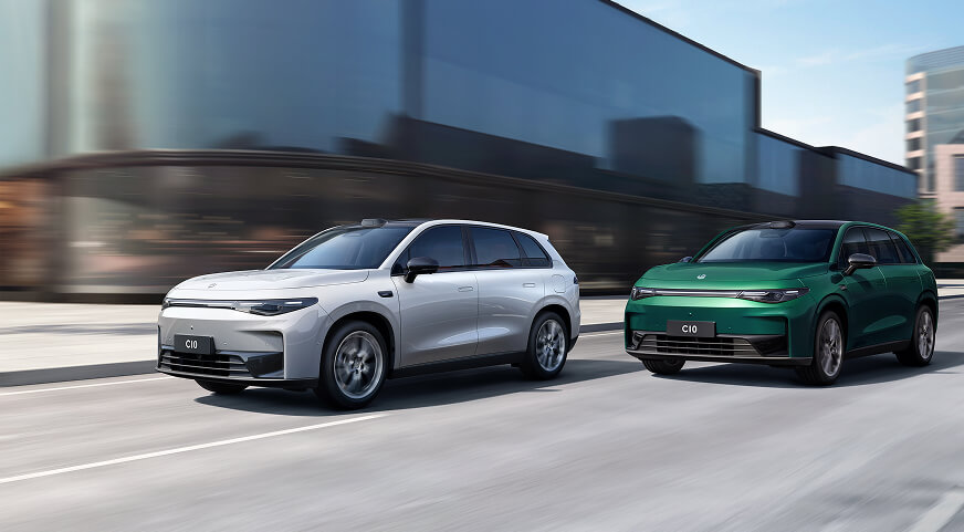 Two Leapmotor C10, one white and one green, driving side by side on a city street with modern buildings in the background