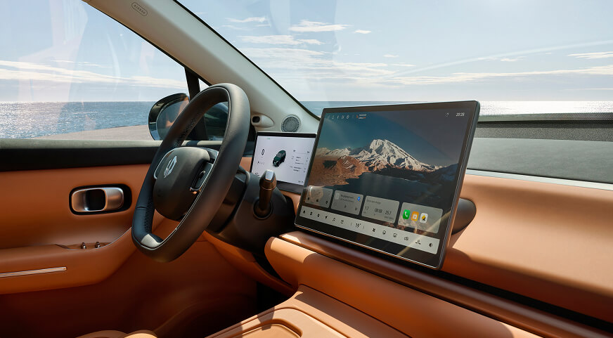 Leapmotor C10 interior with tan leather seats, large central touchscreen displaying mountain image, and ocean view through window