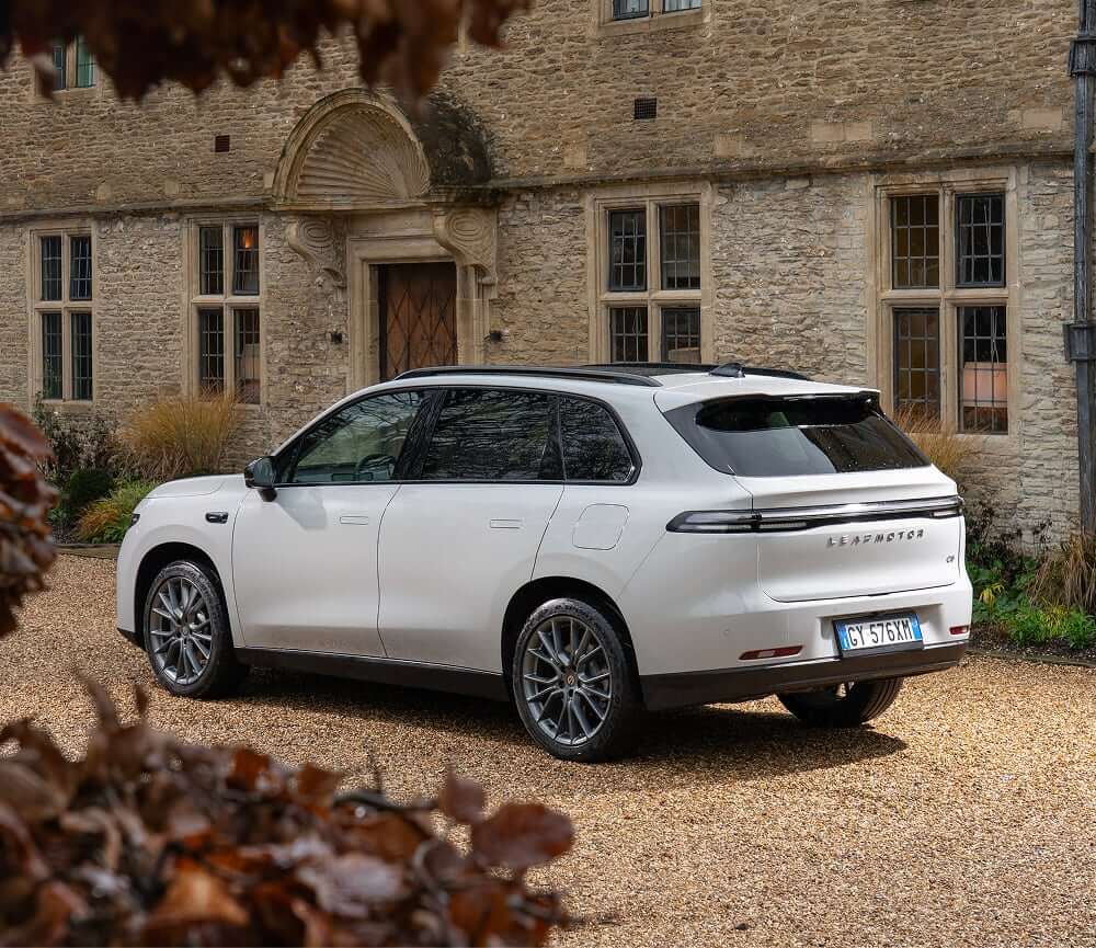 Leapmotor C10 electric SUV parked on gravel outside a historic stone building with multiple windows