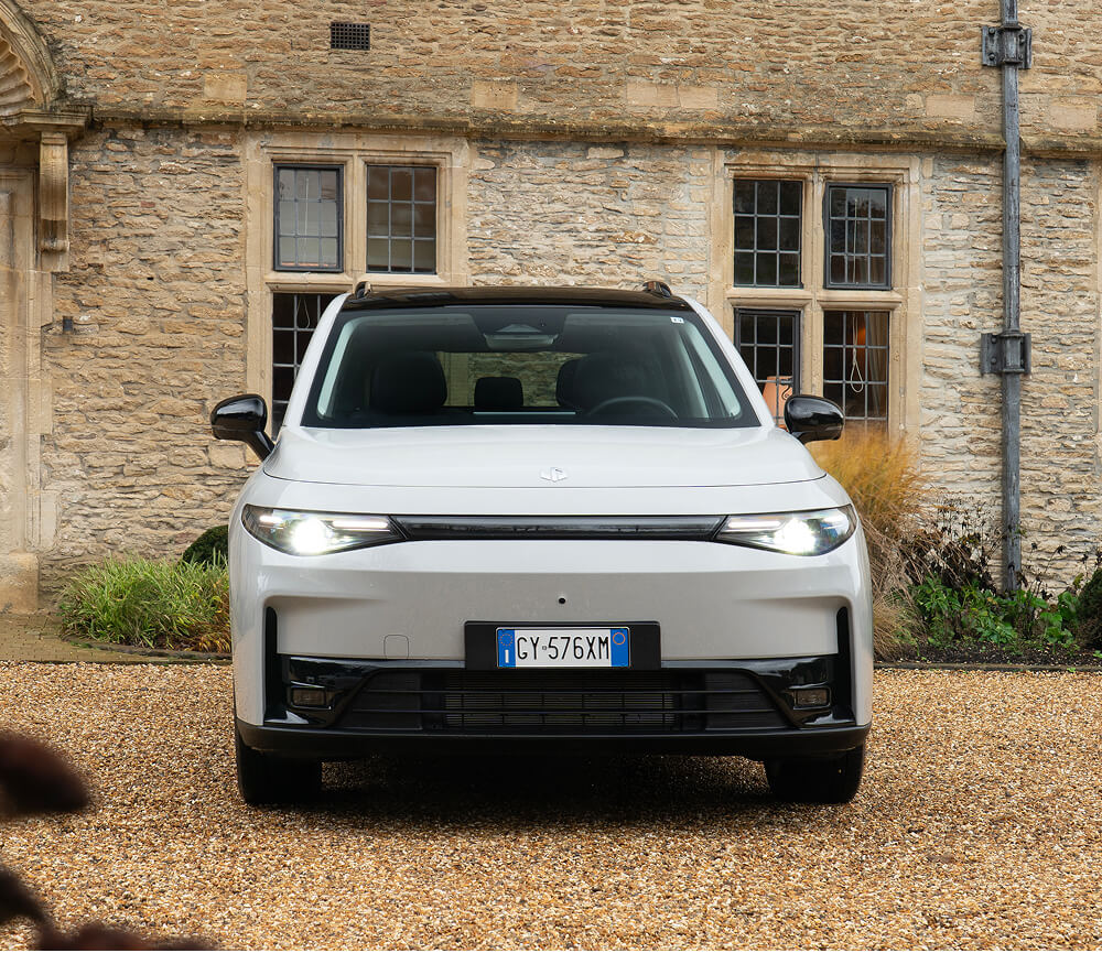 Front view of Leapmotor C10 electric SUV parked on a gravel driveway in front of a stone building with windows