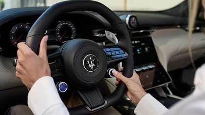 Close up view of Maserati Granturismo steering wheel with driver hands