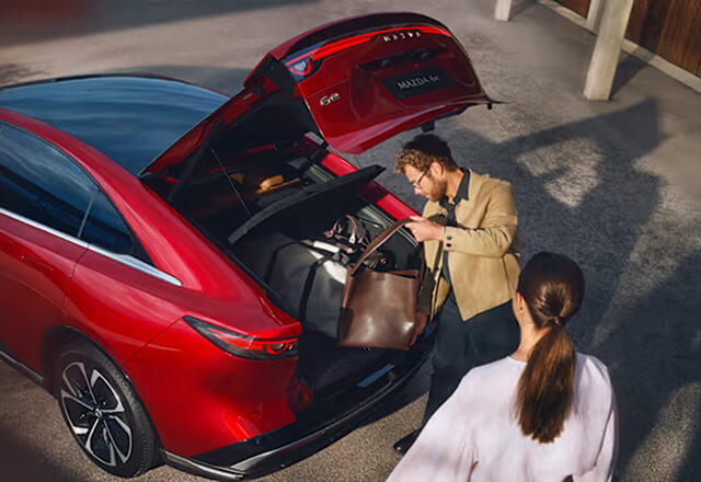 Two people packing luggage into Mazda6e boot