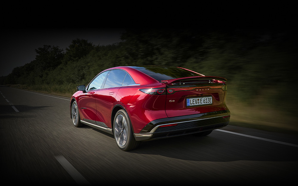 Red Mazda6e travelling along country road