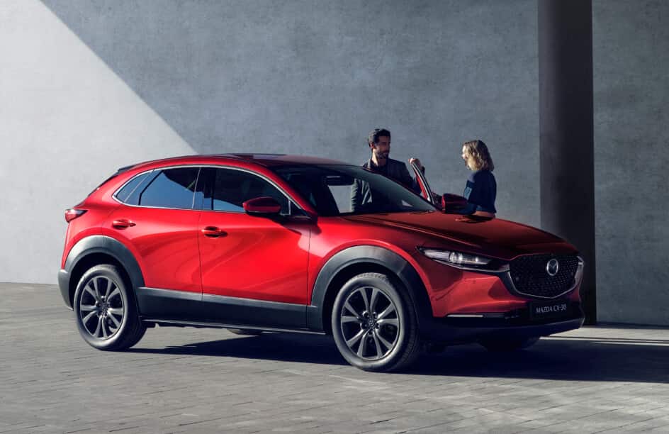 Angled side view of Mazda CX-30 with 2 people standing by passenger door