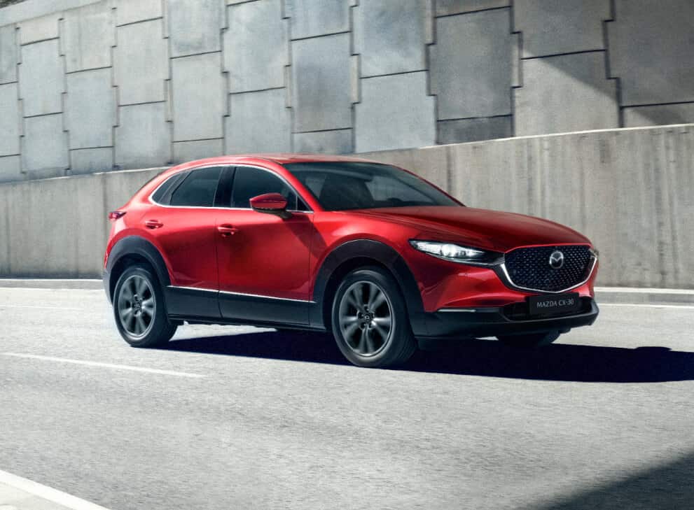 Angled front view of red Mazda CX-30 driving on street