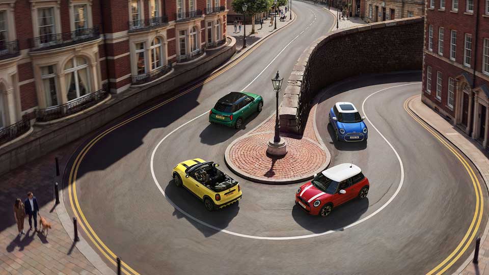 Upward angled view of Mini convertible vehicle driving along the road next to beach