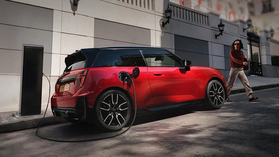 Side angled MINI parked on side of road charging