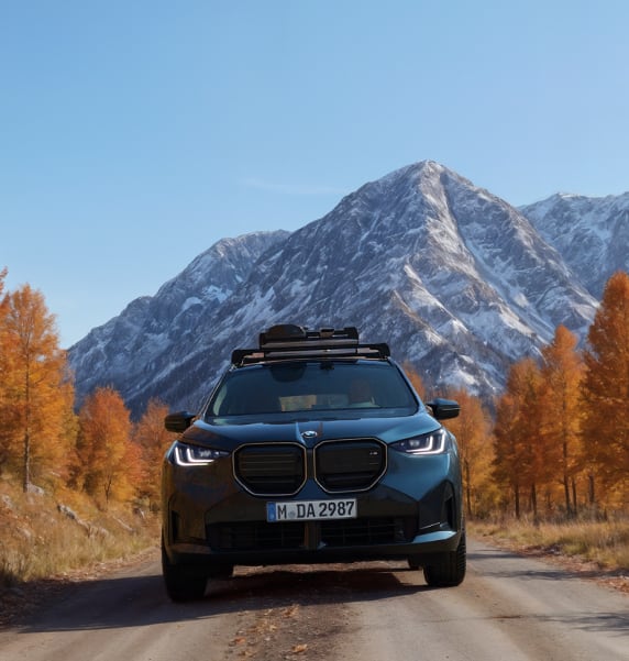 Front angled view of BMW vehicle on the road with mountains in background