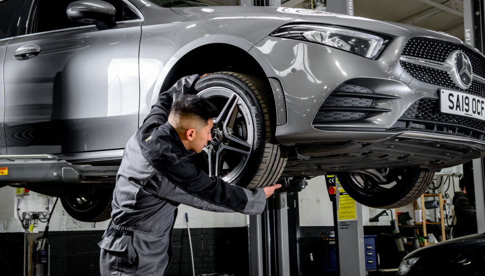 Mechanic checking car tyre for imperfections