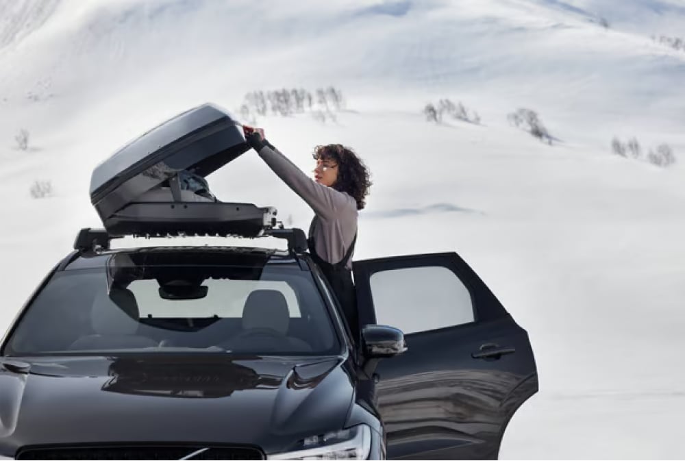 Front view of woman using the Volvo roof box
