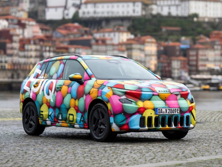 Front angled view of Skoda Epiq with river and city buildings background