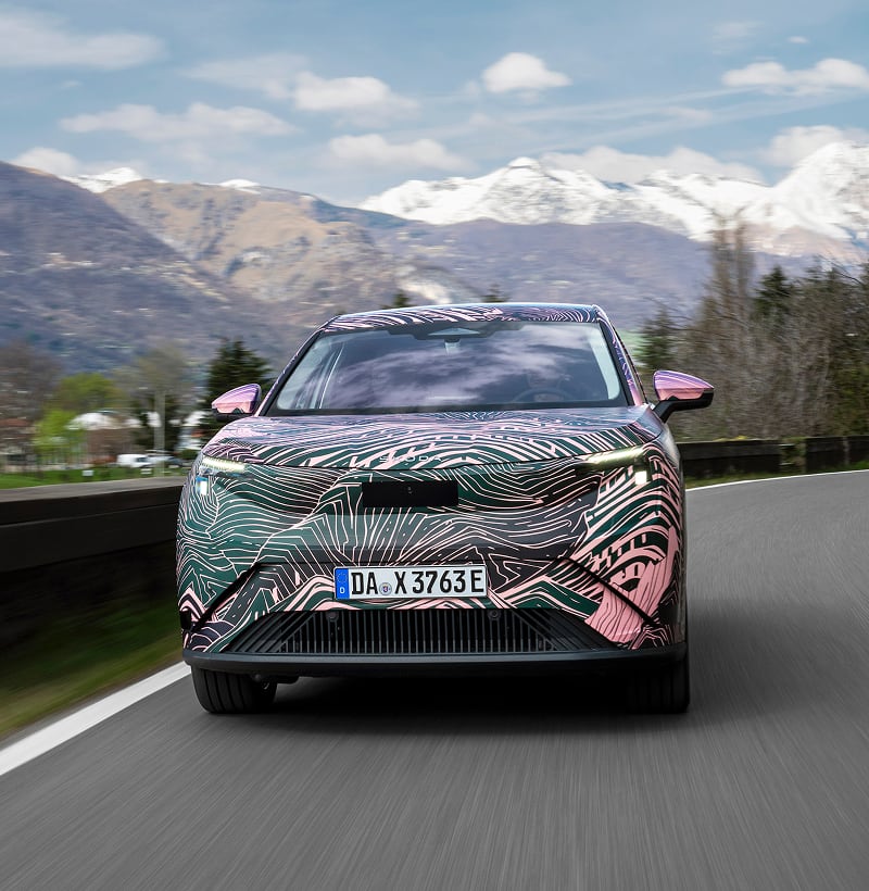Front view of a Skoda Peaq driving on a mountain road in the background