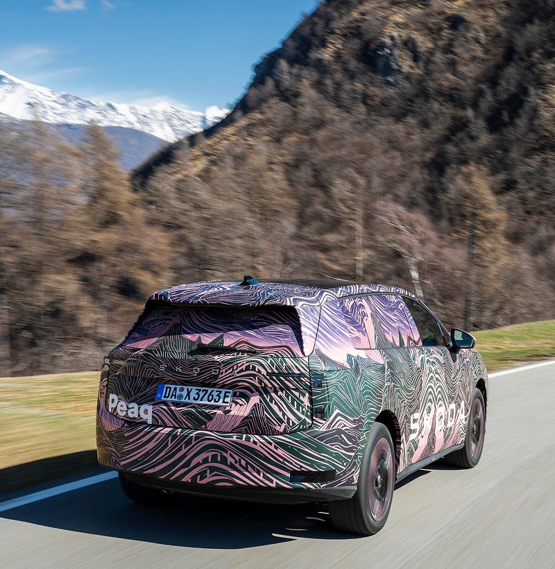 Rear angled view of a Skoda Peaq driving on a mountain road in the background
