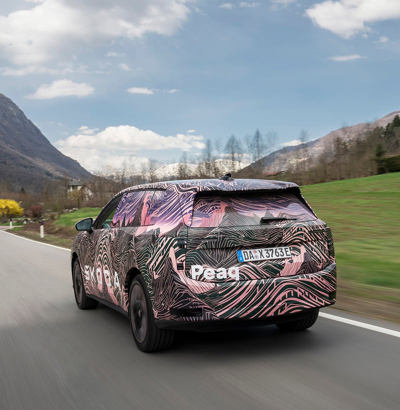 Rear angled view of a Skoda Peaq driving with mountain in the background