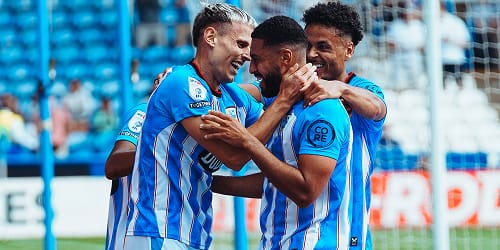 Football players celebrating a goal with a group hug.