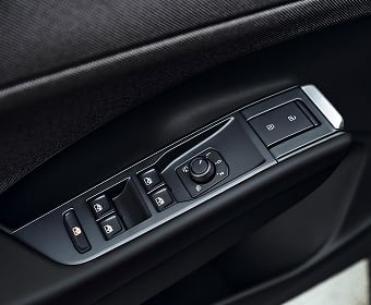 Car door panel showing window controls, side mirror adjustment knob, and door lock buttons in a sleek black design