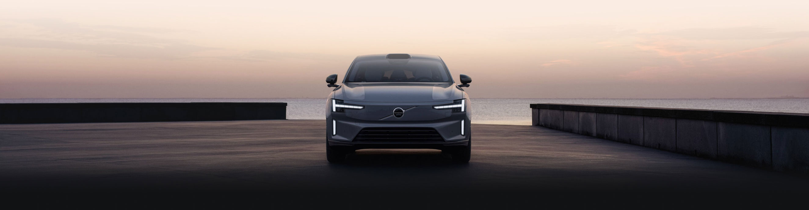 Front view of the Volvo ES90 parked at a waterfront at dusk