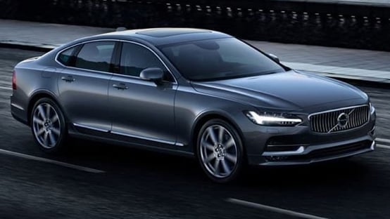 Dark grey Volvo S90 driving across a bridge.